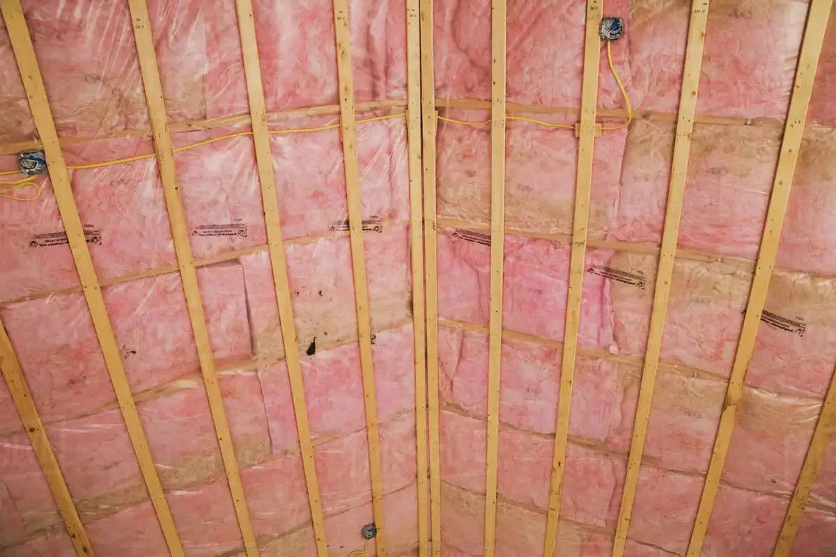 Pink fiberglass insulation installed between wooden rafters for exposed fiberglass solutions