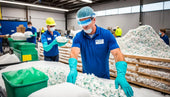 Workers in protective gear sorting recycled plastic materials in an industrial facility.