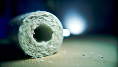 Close-up of a hollow white mineral wool insulation tube with loose fibres