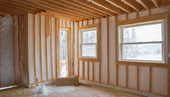 Unfinished room showcasing exposed wooden framing and spray foam insulation installation.